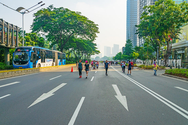 在每周一次的无车日期间，活跃的人们在雅加达市中心苏迪曼-塔林路(Sudirman-Thamrin road)的一辆巴士附近散步或慢跑